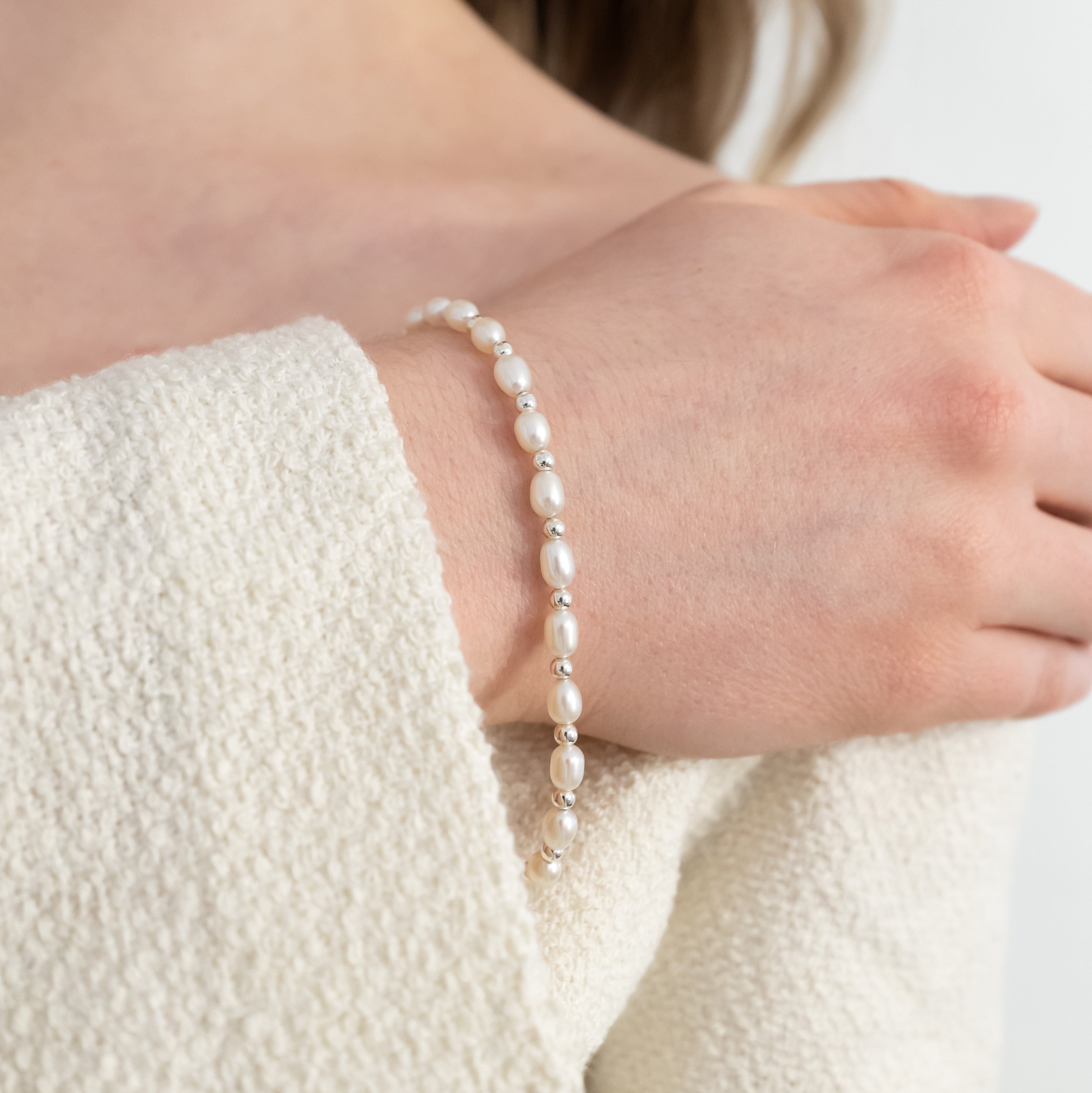 Pearl bracelet on a person's wrist with a neutral background