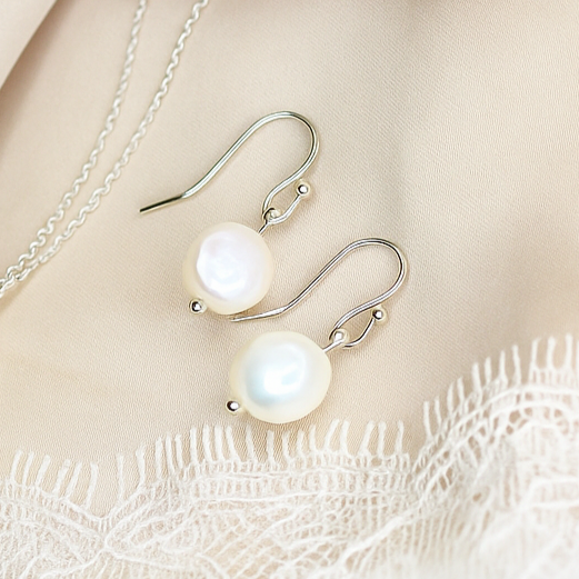 Pearl necklace and earrings on a soft fabric background