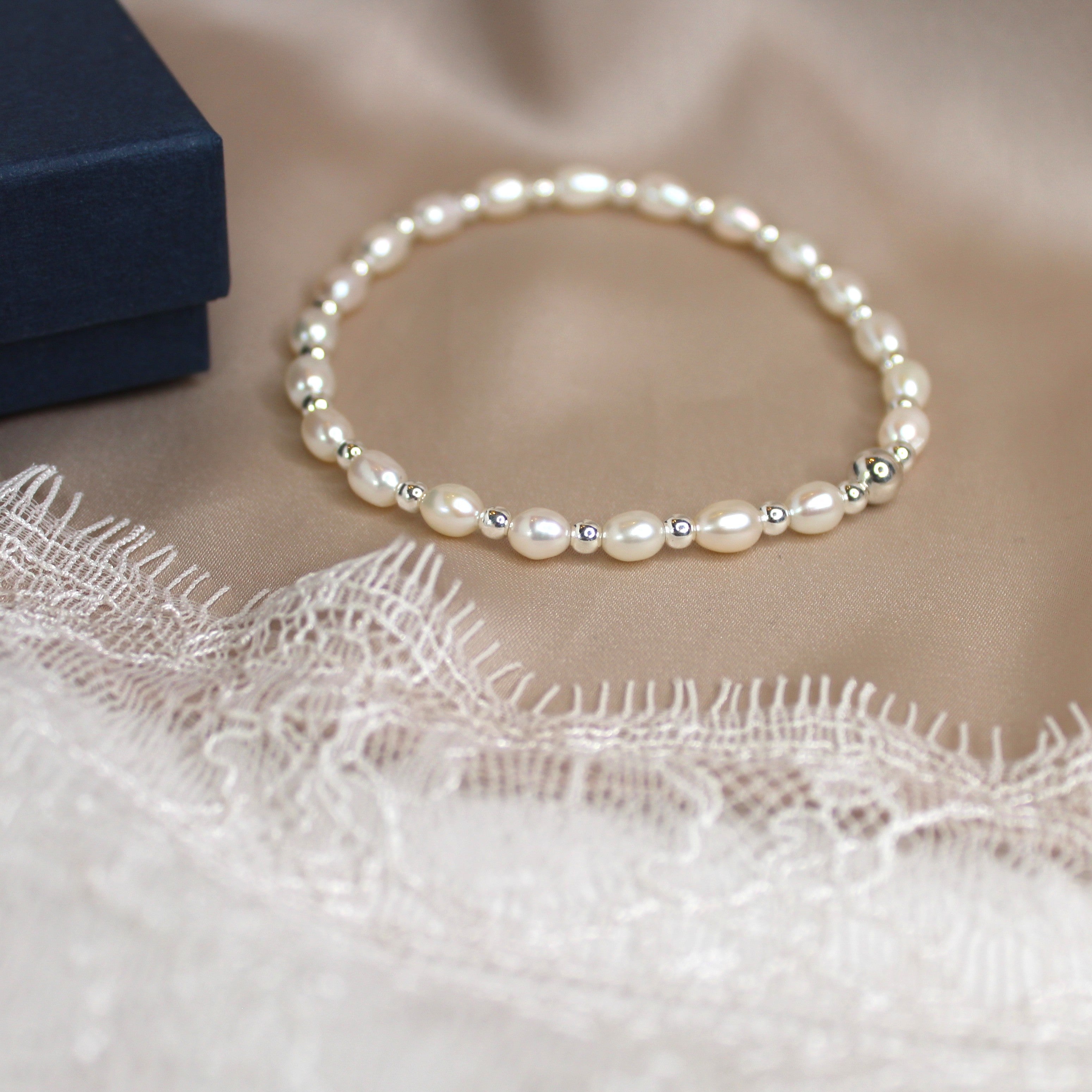 Pearl bracelet on a lace fabric with a blue box in the background