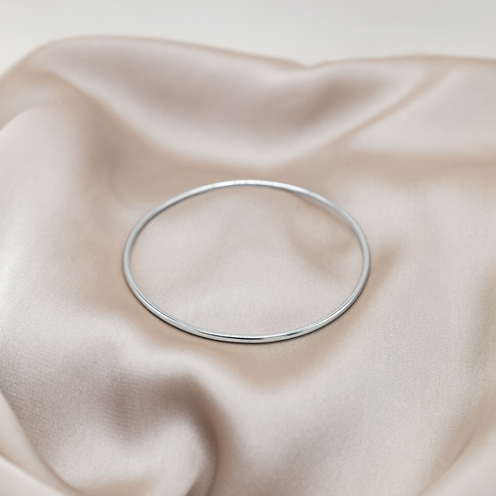 Silver bracelet on a soft beige fabric background